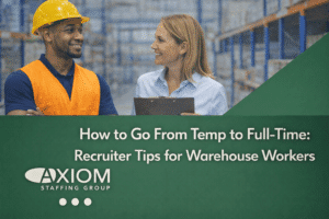 Warehouse worker wearing a safety vest and hard hat speaking with a recruiter holding a clipboard inside a distribution center, featured in a banner about transitioning from temporary to full-time warehouse employment at Axiom Staffing Group.